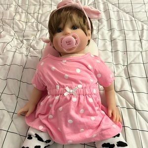 Realistic, reborn doll with tons of pink clothing